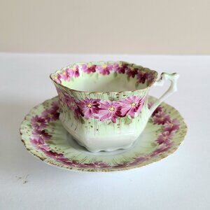 Antique porcelain tea cup with saucer with pink floral design and gold trim.